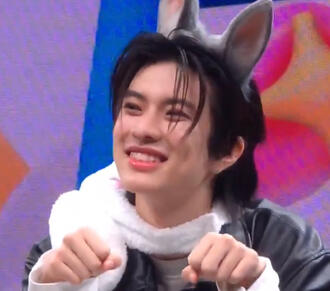 Foto do Aston sorrindo com orelhinhas de coelho e fazendo patinhas com as mãos